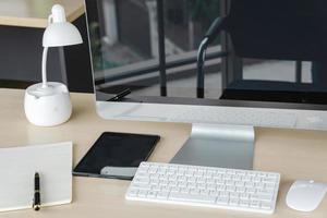 Business and workplace concept. Cup of hot coffee on work desk with computer keyboard Mobile and papers working room. photo
