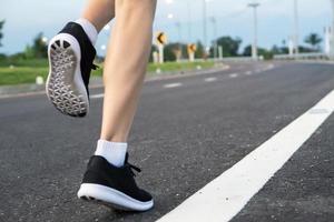 movimienot. piernas de mujer corriendo en la carretera de asfalto. foto