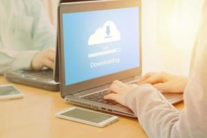 Young employee looking at computer monitor to cloud downloading working day in office photo