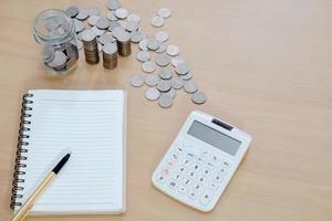 cuaderno de oficina, calculadora, monedas y bolígrafo foto