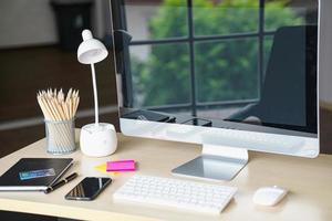 Business and workplace concept. Cup of hot coffee on work desk with computer keyboard Mobile and papers graphs working room. photo