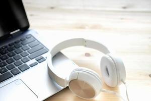 auriculares blancos y ordenador portátil sobre fondo de madera foto