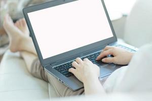 Side view of casual young woman using laptop on sofa at home photo