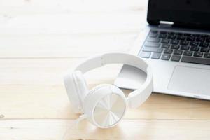 White headphone and laptop computer on wooden background photo