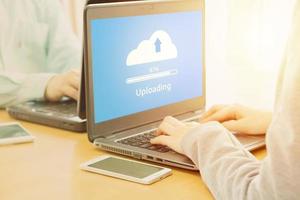 Young employee looking at computer monitor to cloud uploading working day in office photo