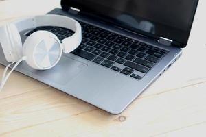 White headphone and laptop computer on wooden background photo