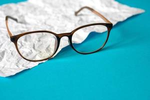 White crumpled paper and blue paper. eyeglass concept. photo