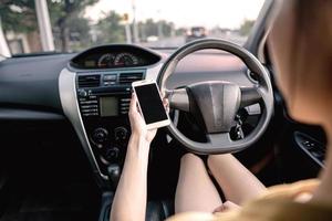 mujer joven en coche revisando su teléfono inteligente mientras conduce foto