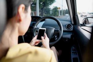 Young woman in car checking her smartphone while driving photo