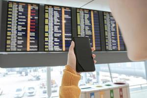 mujer joven comprobando el vuelo en el horario foto