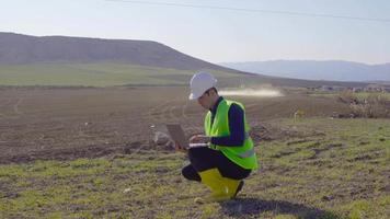 trator agroquímico e engenheiro. a pulverização agrícola é feita pelo trator na terra agrícola do solo. um engenheiro está trabalhando no laptop na mão. video