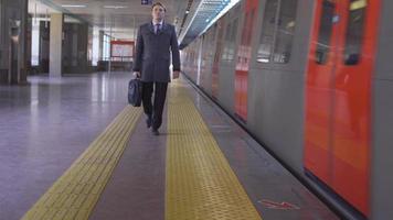 A business man with a bag is walking in the subway. The businessman is walking while the subway is moving next to him. Modern businessman holding a briefcase. video