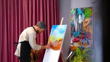 o pintor pinta em um espaço colorido. visão geral do pintor trabalhando em um espaço artístico. video