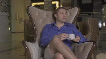 el hombre tomando su café en el vestíbulo del hotel. el hombre que espera en el vestíbulo del hotel está tomando su café y descansando. video