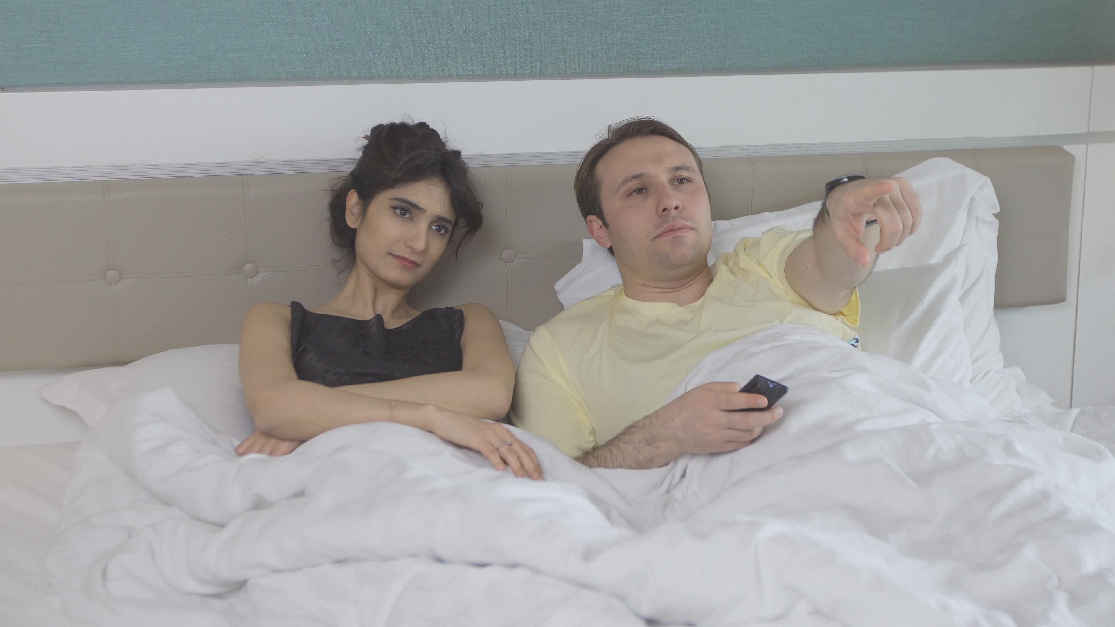 Couple in bedroom. Watching TV. The couple is lying in the bedroom watching  TV and chatting. 8728346 Stock Video at Vecteezy