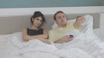 Couple in bedroom. Watching TV. The couple is lying in the bedroom watching TV and chatting. video