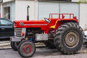 lado turquía 03 de marzo de 2022 el viejo tractor rojo de la marca massey ferguson está estacionado en la calle en un cálido día de verano con el telón de fondo de un estacionamiento foto