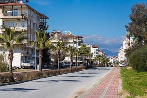 lado turquía 01 de marzo de 2022 calle de la ciudad con casas de varios pisos del mismo tipo, estacionados diferentes autos, tiendas, montañas foto