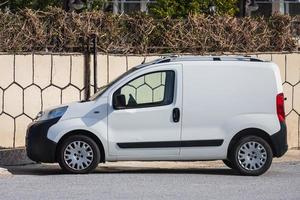 Side  Turkey  February 18 2022  white Fiat Fiorino is parking  on the street on a  summer day against the backdrop of a  fence , park photo