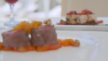 Grilled meat and fish. Dinner plate decorated with sauces and fruits. Dried apricots, walnuts, strawberries. video