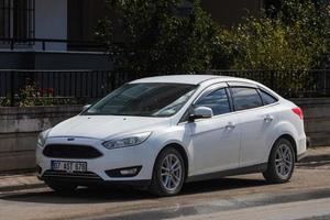 Turquía lateral 01 de marzo de 2022 Ford Focus blanco está estacionado en la calle en un día cálido con el telón de fondo de un parque foto