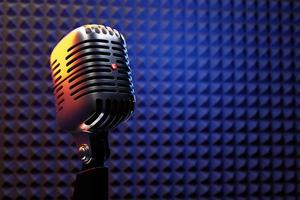 Silver  retro microphone against the backdrop of the walls of a recording studio with good sound insulation . minimal style. 3d rendering
