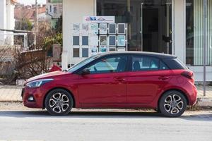 Side  Turkey  February 18 2022    red  Hyundai i20  is parking  on the street on a  summer day against the backdrop of a  shop , park photo