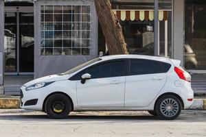 Side  Turkey  February 18 2022 white  Ford Fiesta   is parked  on the street on a warm day against the backdrop of a buildung,   park, fence, shops photo