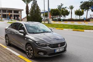 Side Turkey  February 28 2022  gray  Fiat Egea   is parking  on the street on a  summer day against the backdrop of a   hotel, park photo