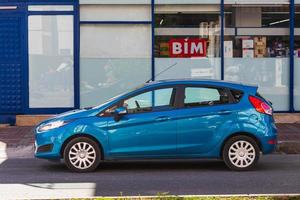 Side Turkey  February 20 2022   blue   Ford Fiesta   is parked  on the street on a warm day against the backdrop of a buildung,   park, fence, shops photo