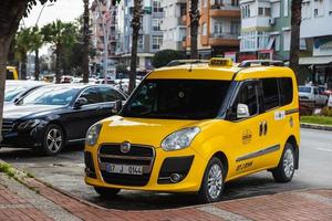 Side Turkey February  20, 2022 yellow taxi Fiat Doblo    is parked  on the street on a warm summer day against the backdrop of a  street, trees photo