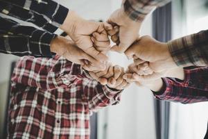 jóvenes empresarios poniendo sus manos juntas foto