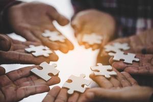 Hands holding piece of blank jigsaw puzzle for teamwork photo