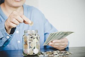 woman hand putting money into jar photo