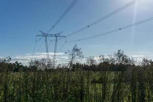 Postes de electricidad de alta tensión cruzando tierras de cultivo foto