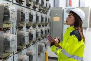 Electrical engineer woman checking voltage at the Power Distribution Cabinet in the control room,preventive maintenance Yearly,Thailand Electrician working at company photo