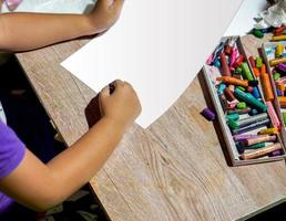 Closeup and crop hands of student holding crayon draw and painting on white paper in art classroom. photo