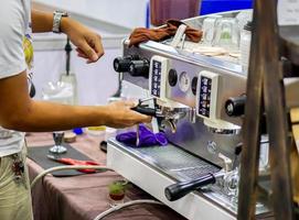 Closeup hands of coffee barista making a fresh coffee by coffee machine for customer in a coffee shop. photo