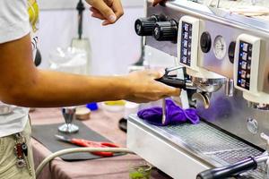 Closeup hands of coffee barista making a fresh coffee by coffee machine for customer in a coffee shop. photo