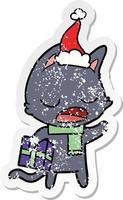 talking cat distressed sticker cartoon of a wearing santa hat vector