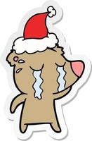 sticker cartoon of a crying bear wearing santa hat vector