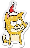 distressed sticker cartoon of a grinning fox wearing santa hat vector