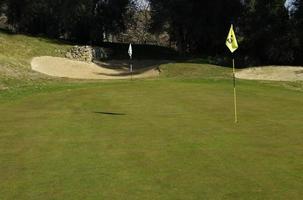 campo de golf con palo de bandera en un día soleado foto