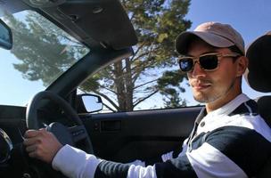 joven con gafas de sol en un coche descapotable foto