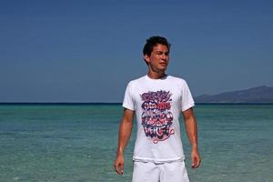 Varadero, Cuba - July 3, 2019 - A young man with a sweaty face and a white shirt with the words - Come into my mind, it's funny here - standing at the shore in Cuba. photo