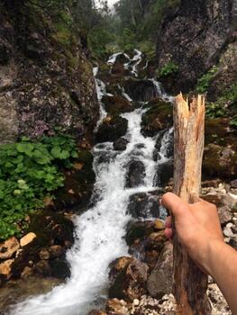 Point of view of a hiker with hiking stick in front of a small mountain river photo