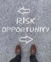 Top view on a man standing in front of the words Risk and Opportunity with arrows pointing to the left and right side of the picture photo