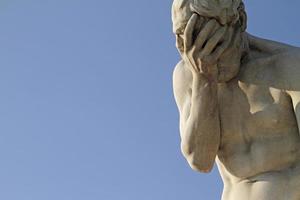 12 June 2022 - Paris, France - A statue with its head in its hand against the blue sky. photo