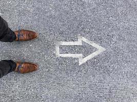 The way forward - Man standing in front of an arrow sign on the floor photo