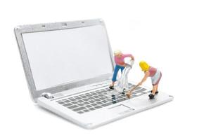 Miniature people cleaning laptop computer on white background photo